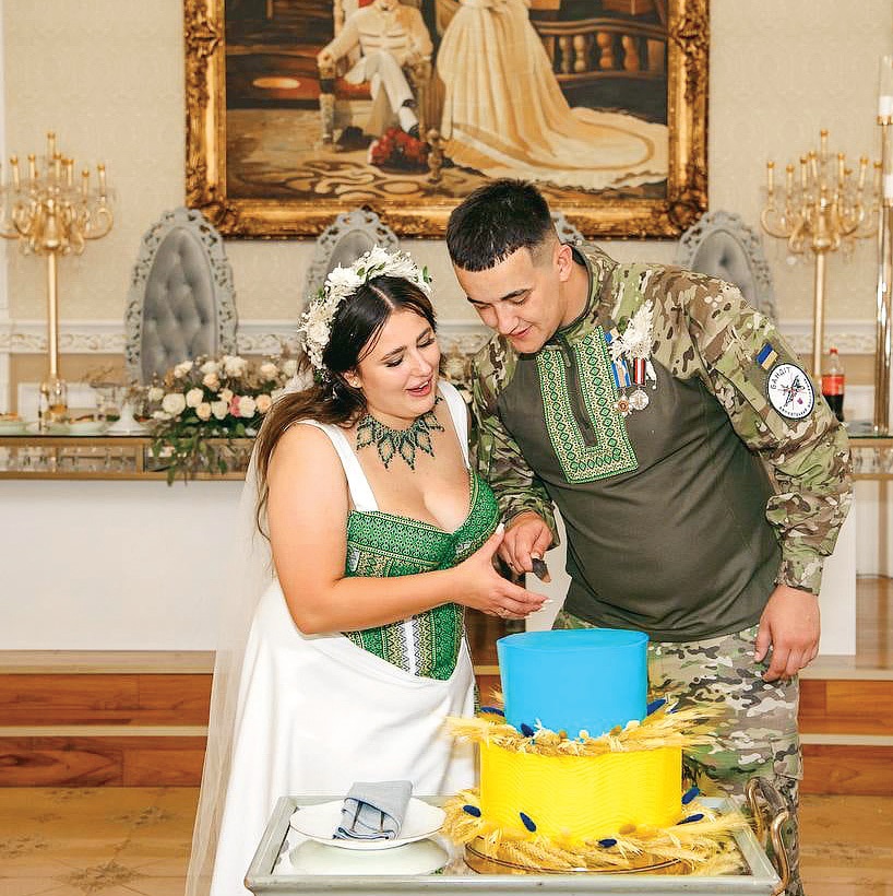 Молодята ріжуть весільний торт у патріотичних кольорах.