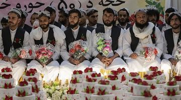 На масову весільну церемонії у Кабулі майбутні чоловіки прийшли з квітами. Де їхні наречені? Чекали в іншій залі... Фото BBC News.