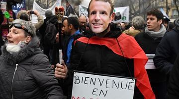 Три роки тому, в січні 2020-го, у Парижі вже протестували проти пенсійної реформи, яку просуває президент Франції. Незадоволений реформою демонстрант у масці Емануеля Макрона - з плакатом "Ласкаво просимо до Макронії". Фото AFP.