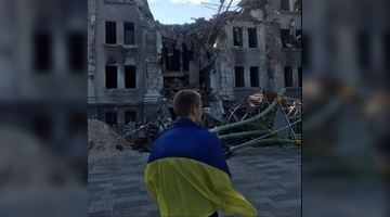 Маріуполь не здається: юнак вийшов до розбомбленого Драмтеатру з прапором України