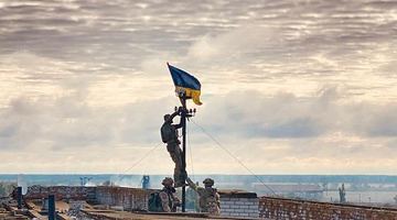 Українські військові встановлюють державний прапор на даху лікарні у визволеному Високопіллі.