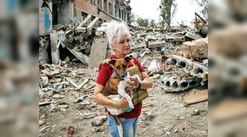 Любов Ярова із собачкою Перемогою - біля розбомбленої школи в Оріхові.